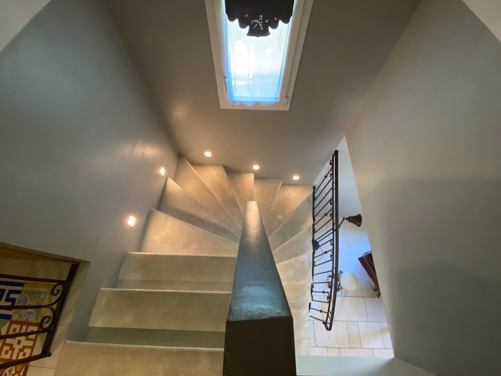 Escalier contemporain éclairé par une verrière et des appliques discrètes