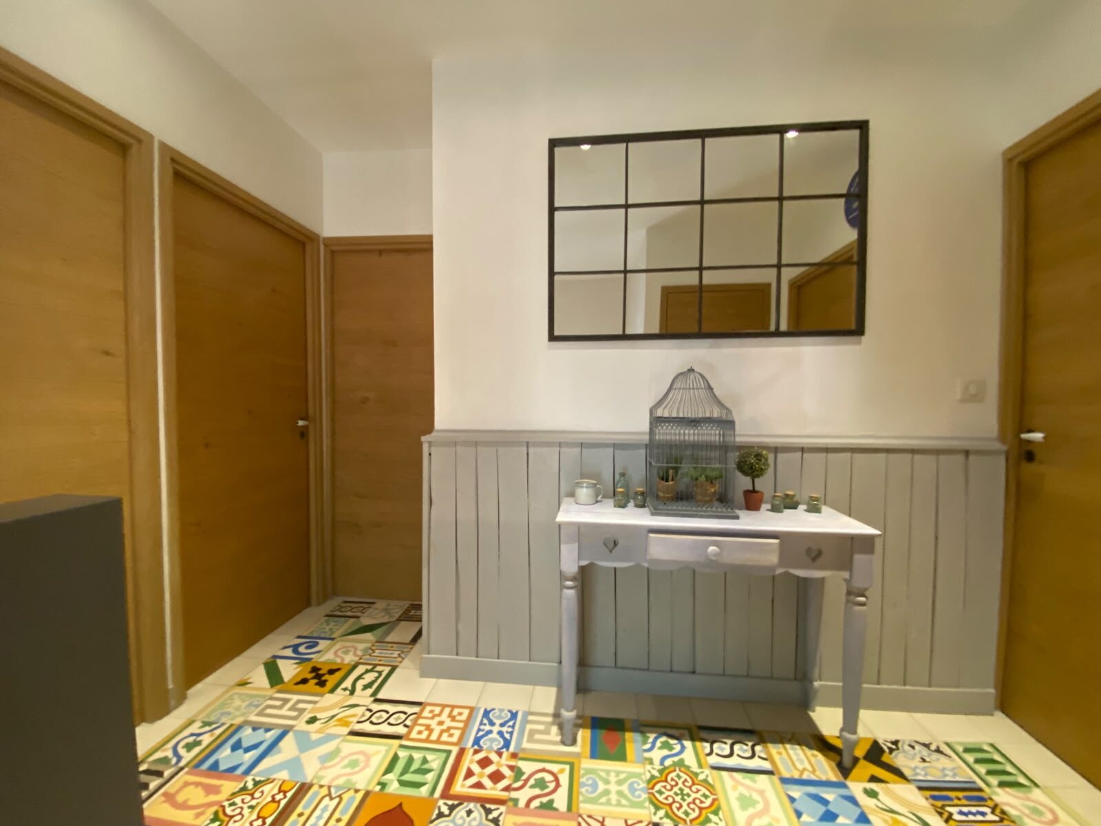 Palier de l’étage aux carreaux colorés, miroir atelier et console claire