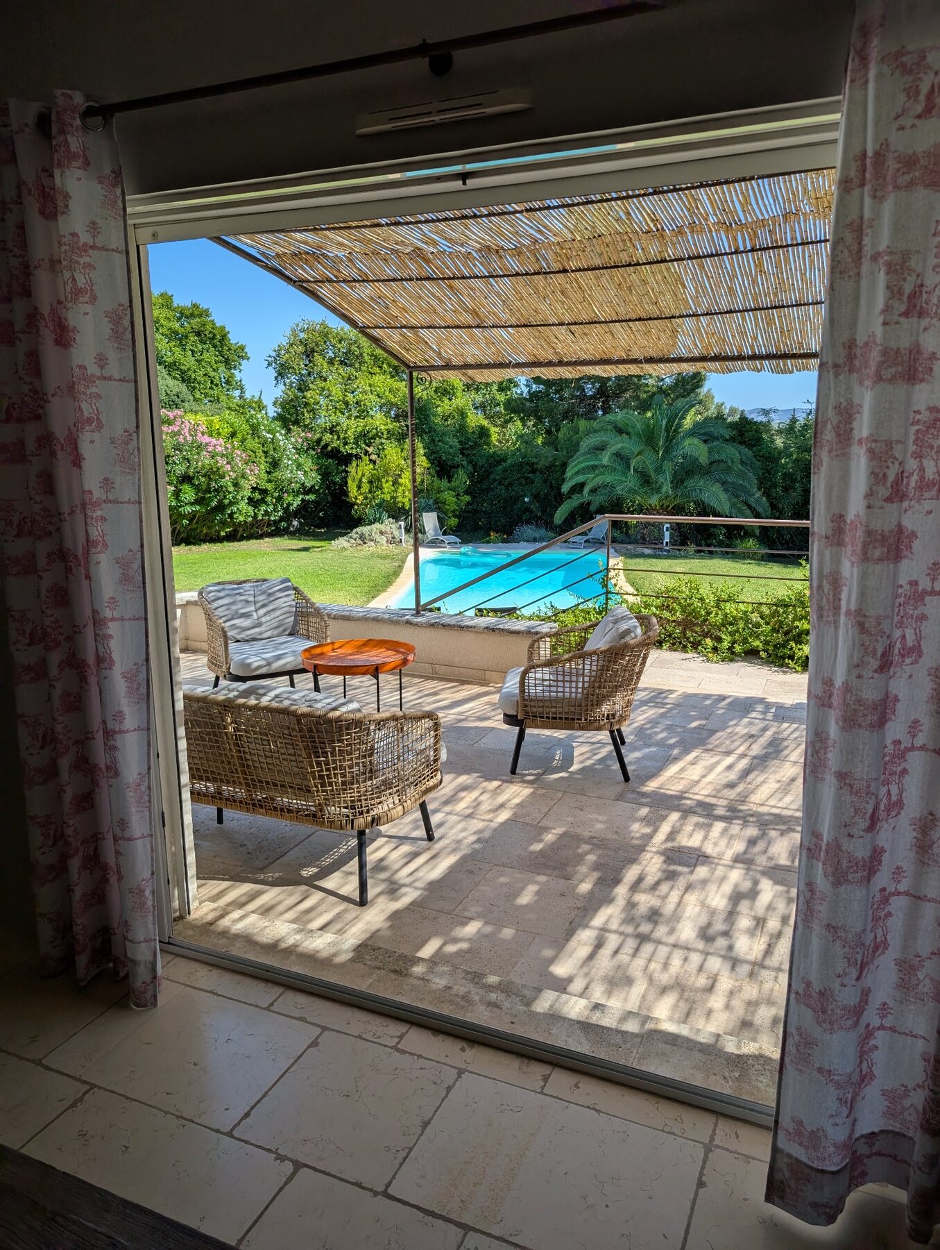 Salon de terrasse ombragé ouvert sur la piscine