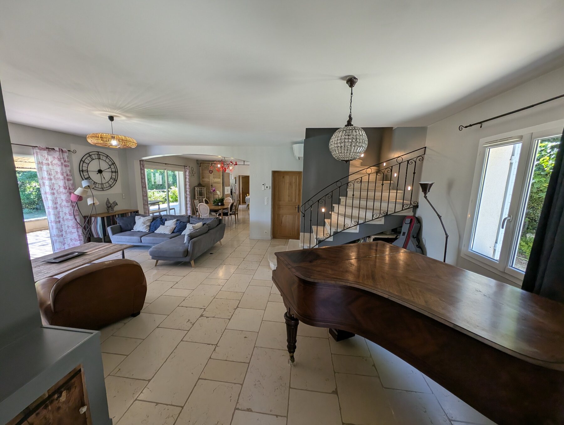 Grand séjour lumineux avec salon, escalier et piano